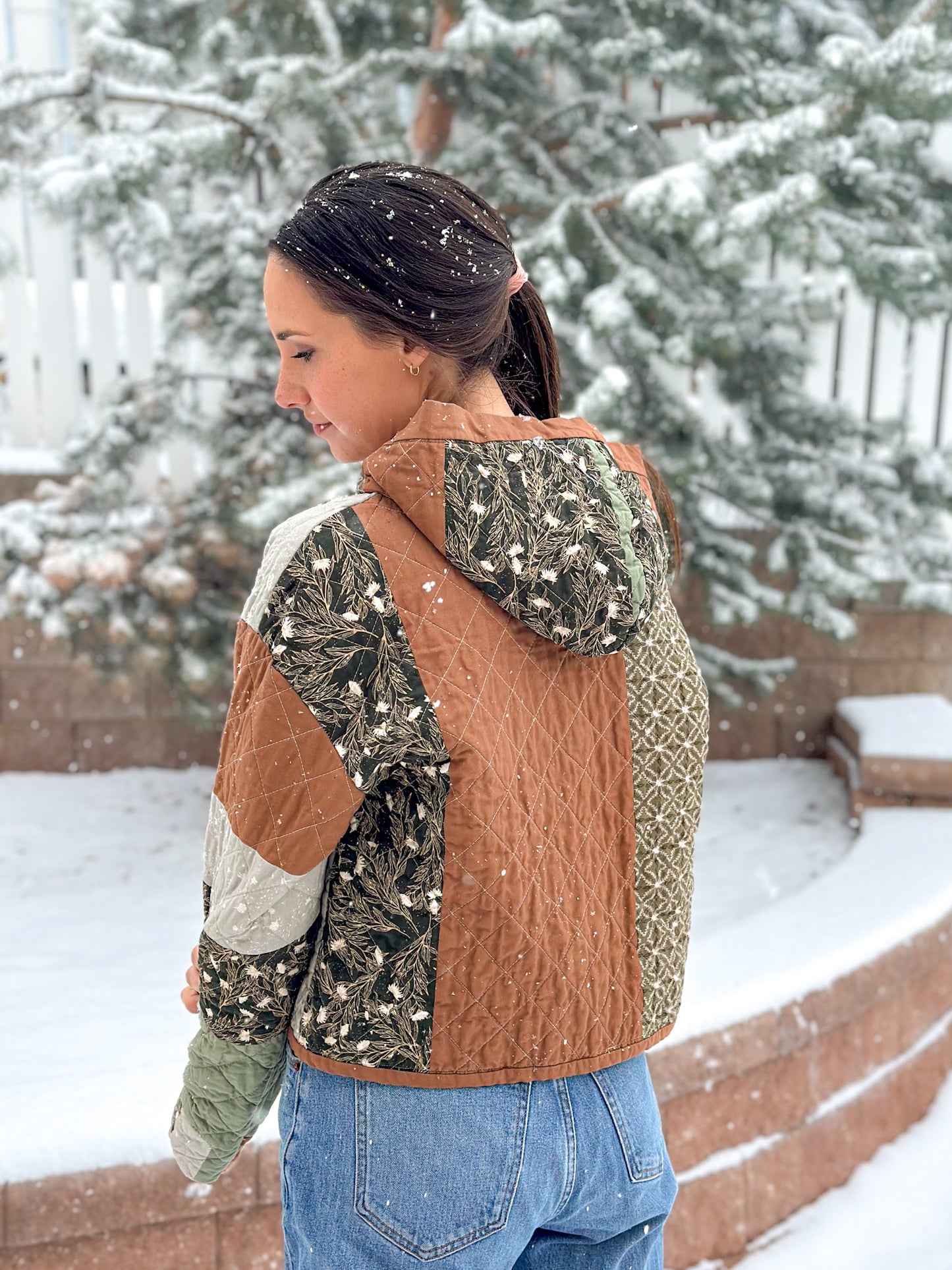 Person wearing a patchwork jacket with a camouflage pattern in a snowy outdoor setting